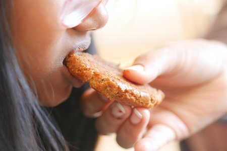 A Child Joyfully Enjoying a Delicious Cookie Given to Them by an Adultの写真素材