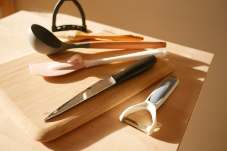 A Variety of Colorful Kitchen Utensils Arranged on a Wooden Cutting Boardの写真素材