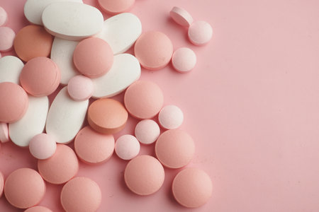 A Colorful Assortment of Various Pills and Tablets Set Against a Pink Backgroundの写真素材