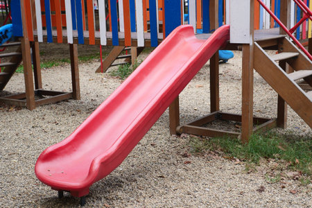 Bright Red Playground Slide Located in Outdoor Recreational Play Areaの写真素材