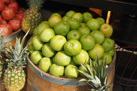 A selection of Fresh Green Apples alongside Pineapples at a Fruit Standの写真素材