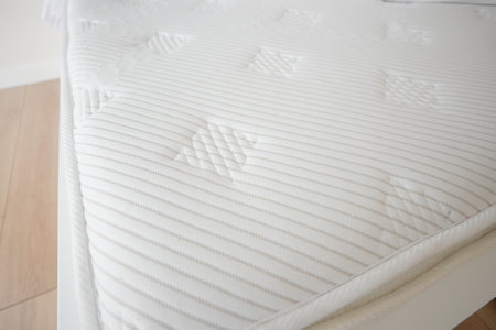 Bed with white orthopedic mattress in a room.の写真素材