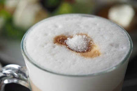 white sugar pouring from a paper packet on a coffee cupの写真素材