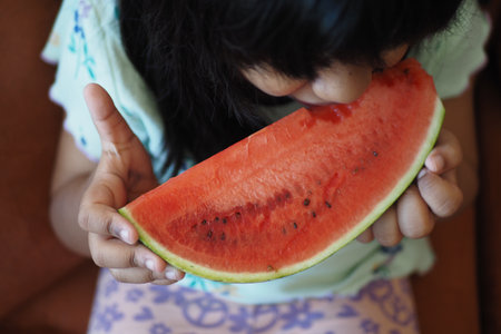 A Happy Young Child Delightedly Enjoys a Fresh, Juicy Slice of Watermelonの写真素材