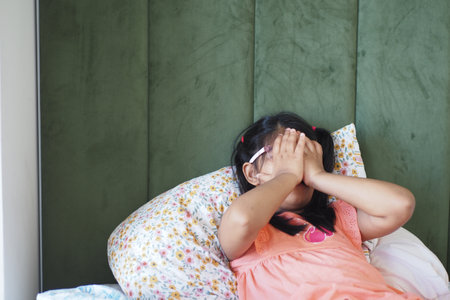 A child expressing various emotions while in a cozy bedroom settingの写真素材