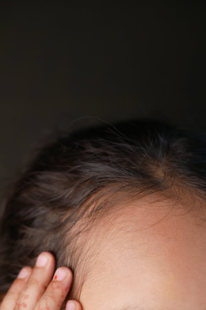 Close-Up of a Childs Hand Near Head with Focus on Skin Textureの写真素材