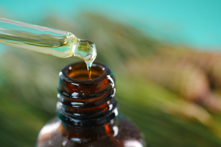 Bottle of pine essential oil and tree branch on white backgroundの写真素材