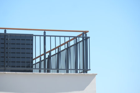 A modern balcony railing stands out vividly against a clear blue skyの写真素材