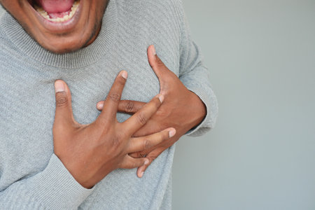 young man suffering pain in heart and holding chest with handの写真素材