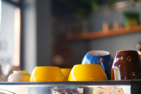 A set of vibrant, colorful ceramic bowls displayed on a shelf in a cozy cafeの写真素材