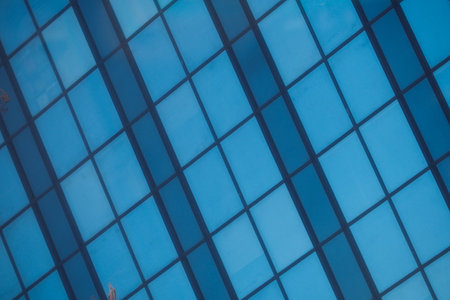 A modern office building facade with large glass windows that reflect its surroundingsの写真素材