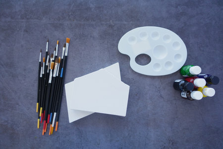 A flat lay display of art supplies brushes, palette, and canvasの写真素材