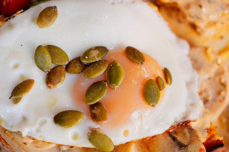 A Fried Egg Topped with Crunchy Pumpkin Seeds on a Plateの写真素材