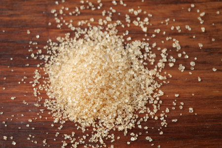 This image features a closeup view of a pile of brown sugar resting on a wooden surfaceの写真素材