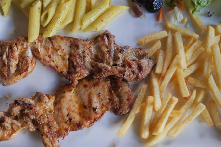 Grilled chicken with pasta and crispy fries makes a satisfying mealの写真素材