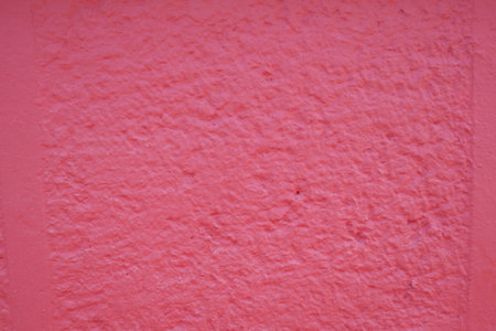 This wall features a textured pink color with a rough and unique surfaceの写真素材