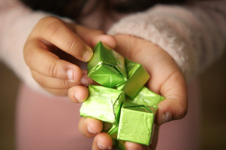A Childs Hands Holding Colorful Green Wrapped Candies and Treatsの写真素材