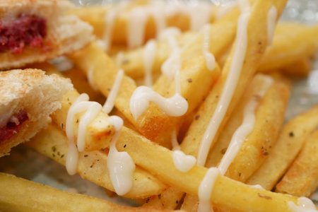 pouring Mayonnaise and French Fries served on a plateの写真素材