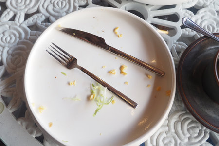 An empty plate with a spoon rests after a meal has been enjoyedの写真素材