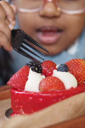 A Happy Child Delightfully Enjoys a Delicious Berry Dessert Using a Forkの写真素材