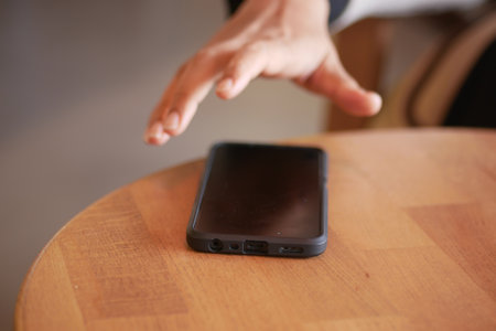 A hand grabbing and picking up mobile phone on the table.の写真素材