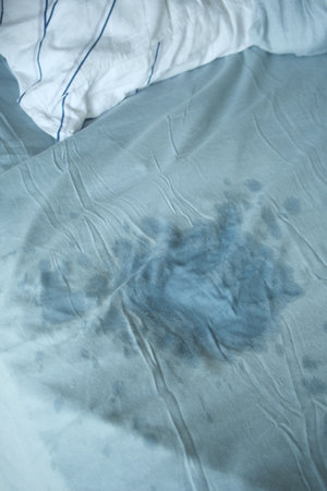 A visible stain on a light blue bedsheetの写真素材