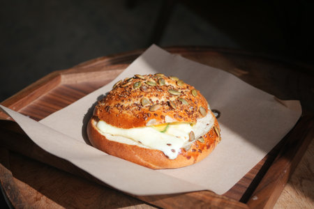 A Delicious CreamFilled Bun Displayed on a Rustic Wooden Platterの写真素材