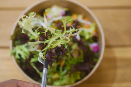 Healthy Organic Salad Bowl with Fresh Mixed Greens on Wooden Tableの写真素材
