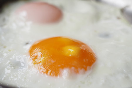 A CloseUp View of Fried Eggs Cooking in a Pan, Perfect for Breakfastの写真素材