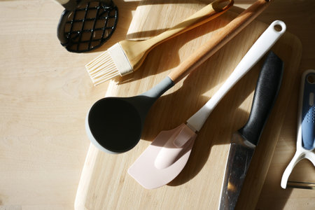 Various Types of Kitchen Utensils Arranged on a Wooden Cutting Boardの写真素材
