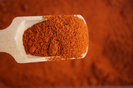 A Detailed CloseUp Image of Red Paprika Powder in a Wooden Spoonの写真素材