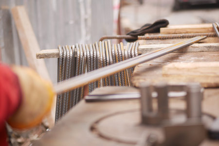 Construction Worker Using Metalwork Equipment on Steel Rods at Worksite