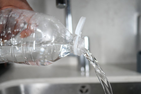 Water is being poured from a plastic bottle into a clean kitchen sinkの写真素材