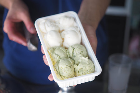 scoops of white and green ice cream in a plastic container
