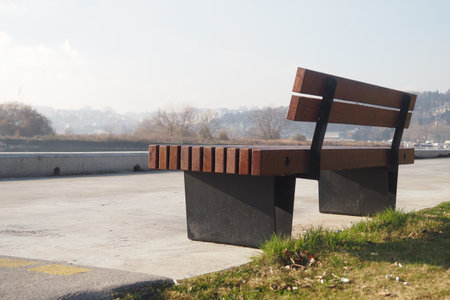 A Serene Park Bench Positioned Gracefully Beneath a Bright Blue Sky