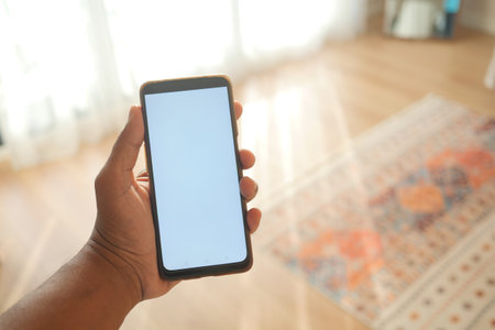 Blank Smartphone Display in Hands with Bright Indoor Lightingの写真素材