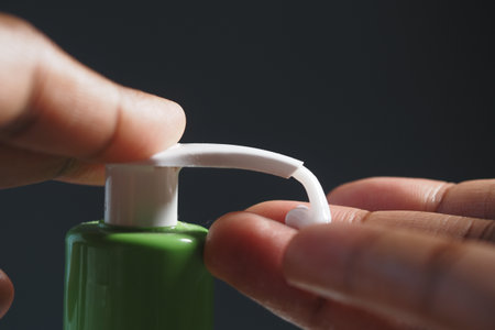 This is a closeup view of hand pumping green lotion from a bottleの写真素材