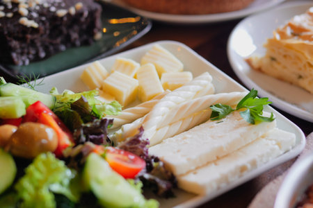 An exquisite and delicious platter featuring fresh salad and gourmet cheeseの写真素材