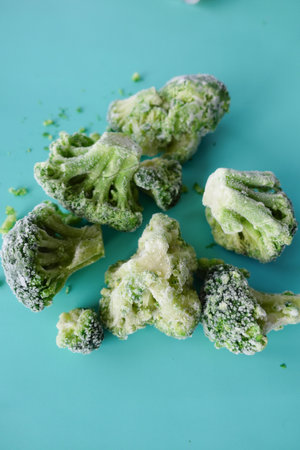 Freshly Frozen Broccoli is Artfully Arranged on a Beautifully Vibrant Turquoise Backgroundの写真素材