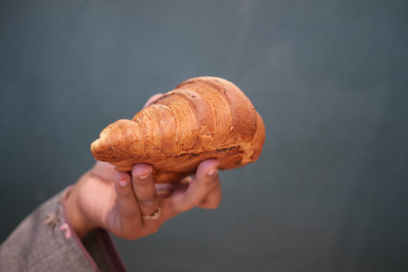 A Hand Gently Holding a Freshly Baked, Golden Brown Croissant