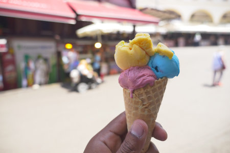 Colorful ice cream cone with yellow, blue, and pink scoops is a cheerful summer dessert