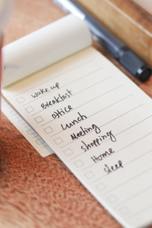 To do list in notebook with office suppliers on desk.の写真素材