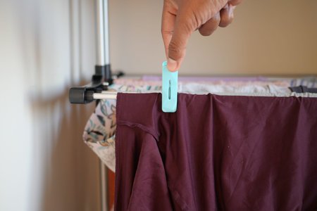 Hand clips cloth to drying rack in indoor setting