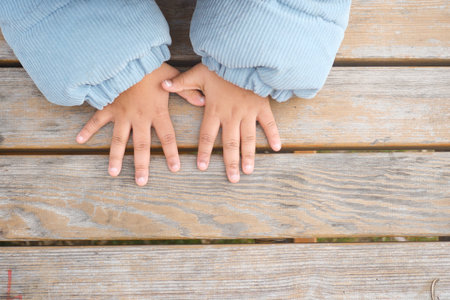 Child Hands resting on a wooden table in a cozy settingの写真素材