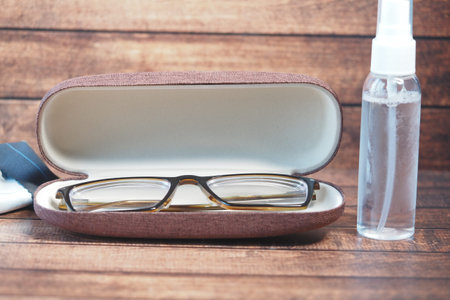 Eyeglasses and cleaning spray on a wooden surfaceの写真素材