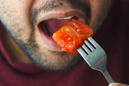 Man enjoying a bite of grilled vegetable at meal timeの写真素材
