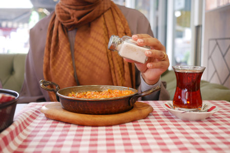 woman pouring salt on Turkish Menemen omelet in a frying pan. .の写真素材