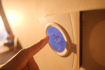 Adjusting the thermostat in a cozy homeの写真素材