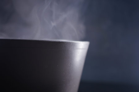 Steam rises from a warm bowl of soup in a dark settingの写真素材