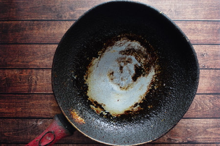 Worn frying pan showing signs of use on wooden surface